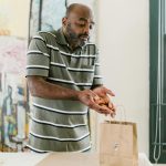 Man prepares handcrafted candles for packaging in a creative workspace, showcasing entrepreneurship.